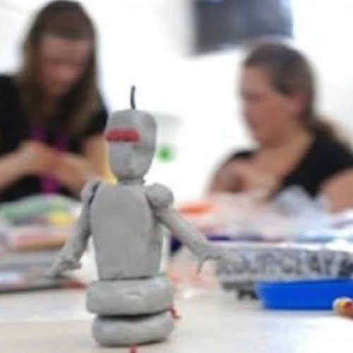 image of a plasticine robot in the foreground and two participants in the background