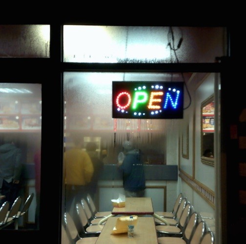 images looking through a cafe window at night. the open sign is lit up in neon colours - email xxxadamjpg@gmail.com for further info.