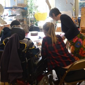 Image of lynn standing over a table while the participants work on their paintings