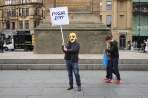 a man wearing a mask with a sign saying 'personal debt'. his mask is love heart Emoticon 