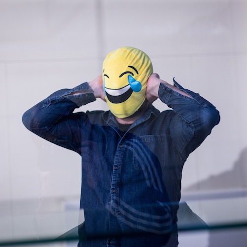 a man with a laughing emoticon mask over his head